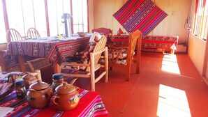 Una habitación con una mesa de madera preparada para comer, una silla y un tapete tejido colorido en el suelo.