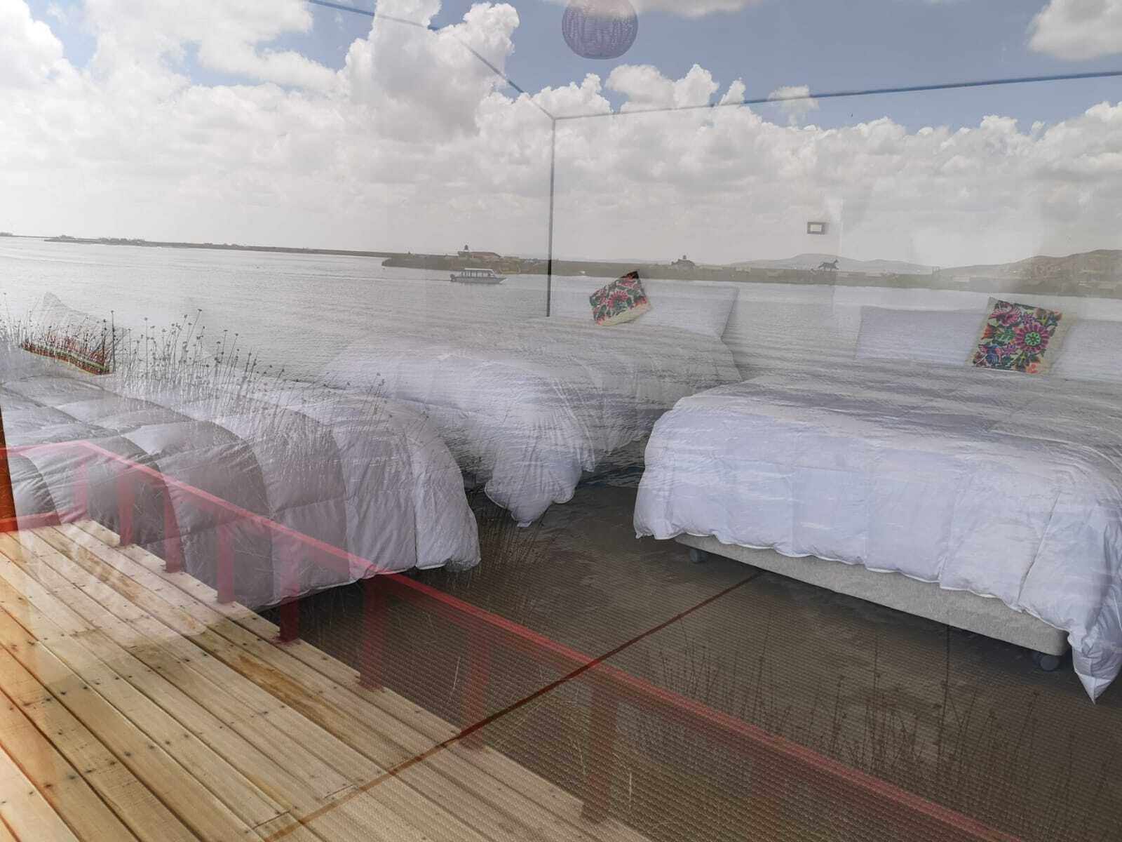 Een kamer met twee bedden, uitzicht op zee en een houten terras.