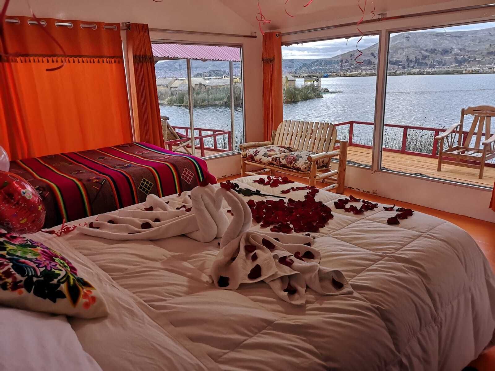 Ein Schlafzimmer mit Bett, Stuhl, Fenster mit Seeblick und Bergblick sowie einem Balkon mit Sitzgelegenheiten.