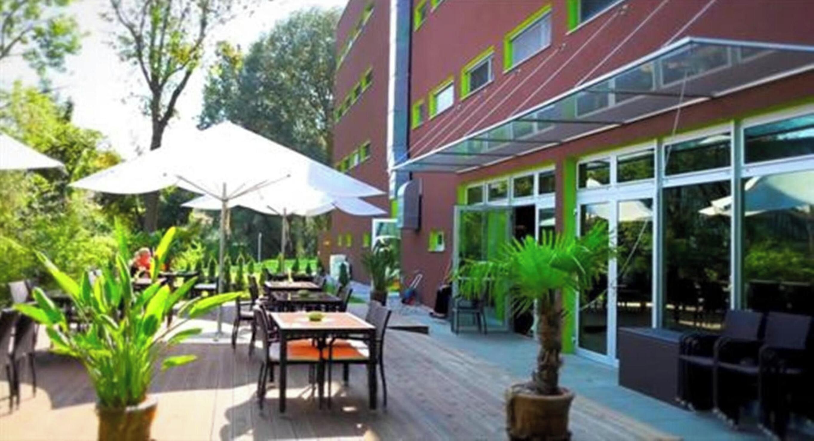 An outdoor patio area with tables and chairs, surrounded by glass doors and windows.