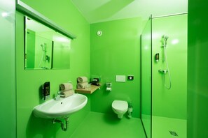 Et badeværelse med vask, toilet og bruser.