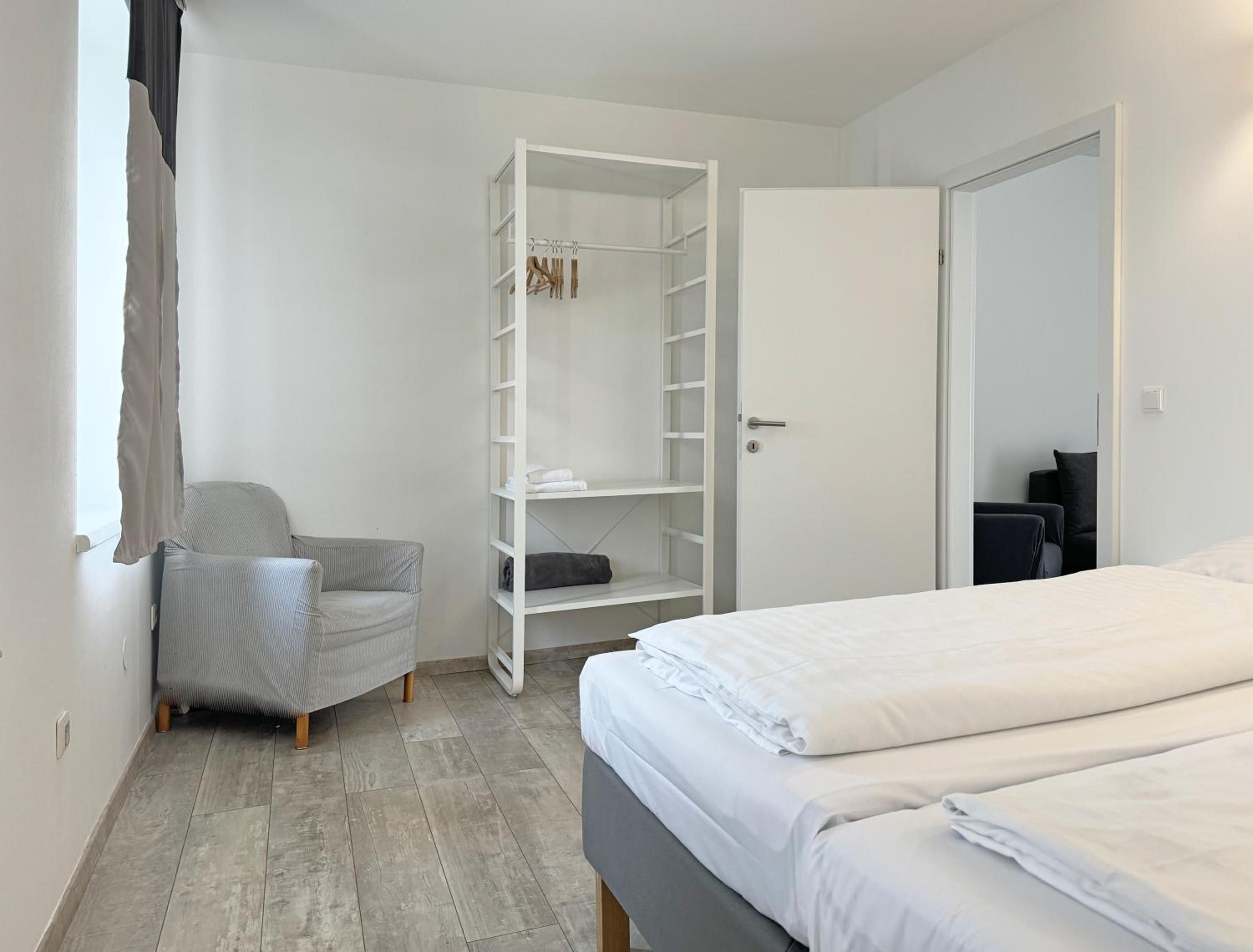 Una camera da letto con un letto, una sedia, un armadio e una porta.