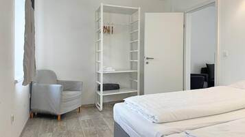 Una camera da letto con un letto, una sedia, un armadio e una porta.