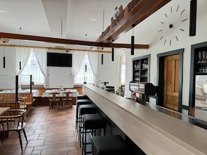 Un restaurant avec un long comptoir, des tabourets de bar et une horloge au mur.
