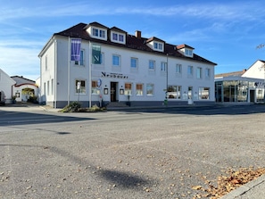 A two-story building with a sign reading 'Neubauer' and a 'Schwarzwald' sign on the right.