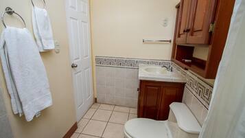 Un baño pequeño con inodoro, lavamanos y armarios de madera.