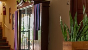 A wooden cabinet with a glass door, a staircase, and a large potted plant. - Hotel y Desayuno Colibri (Managua)