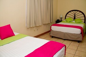 A hotel room with two beds, each with a distinct color scheme. - Hotel y Desayuno Colibri (Managua)