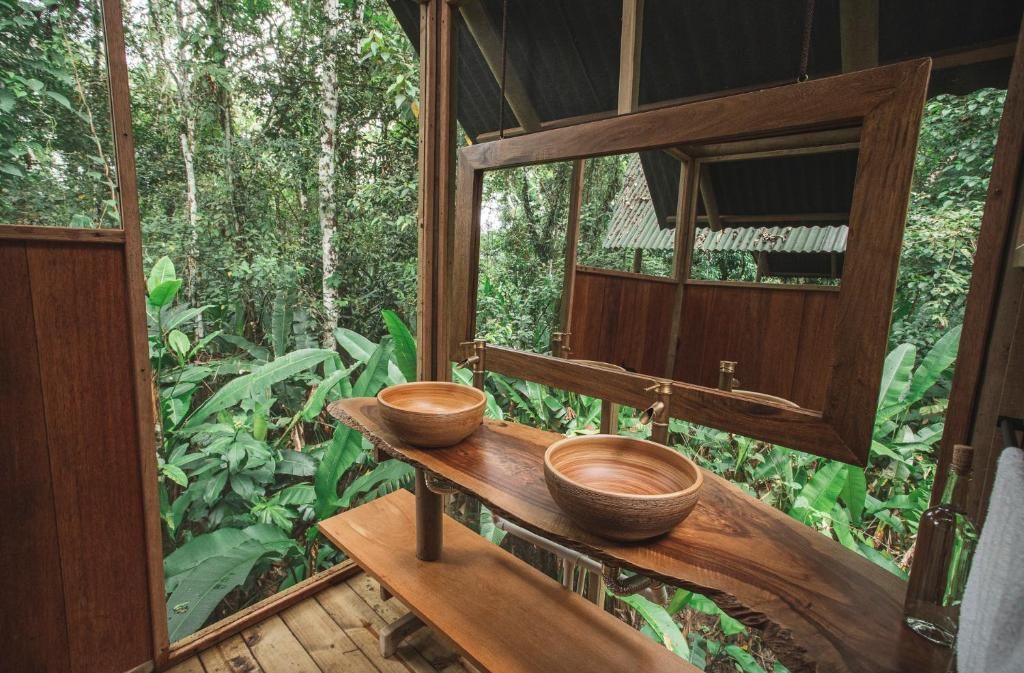 A wooden bathroom with a large window, two wooden bowls, and a bench.