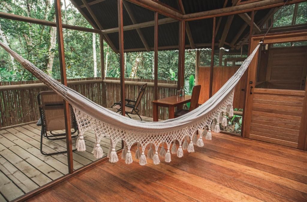A hammock on a wooden deck with a view of the forest.
