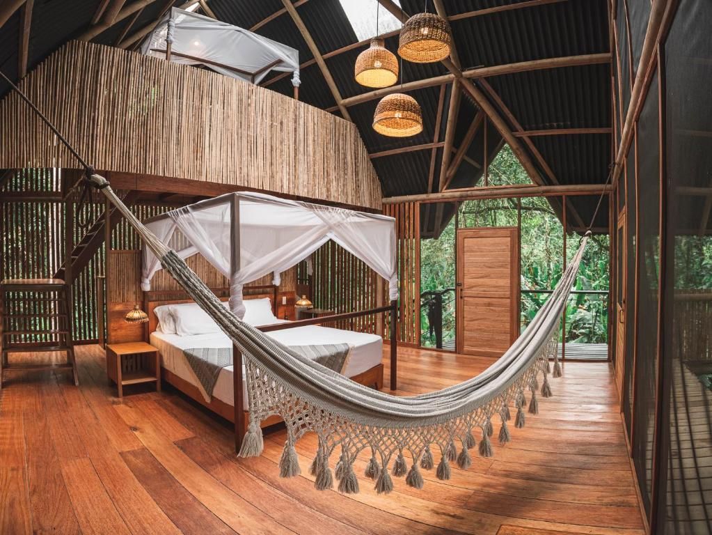 A hammock bed in a wooden room with a view of greenery outside.