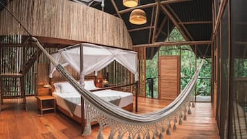 A hammock bed in a wooden room with a view of greenery outside.