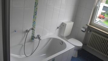 Ein Badezimmer mit Badewanne, Toilette und einem Fenster.