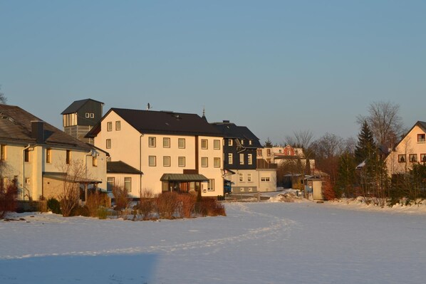 A residential area with multiple houses, a clear sky, and a snow-covered ground.