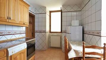 A compact kitchen with wooden cabinets, a tiled backsplash, a built-in oven, and a dining area with a table and chairs.
