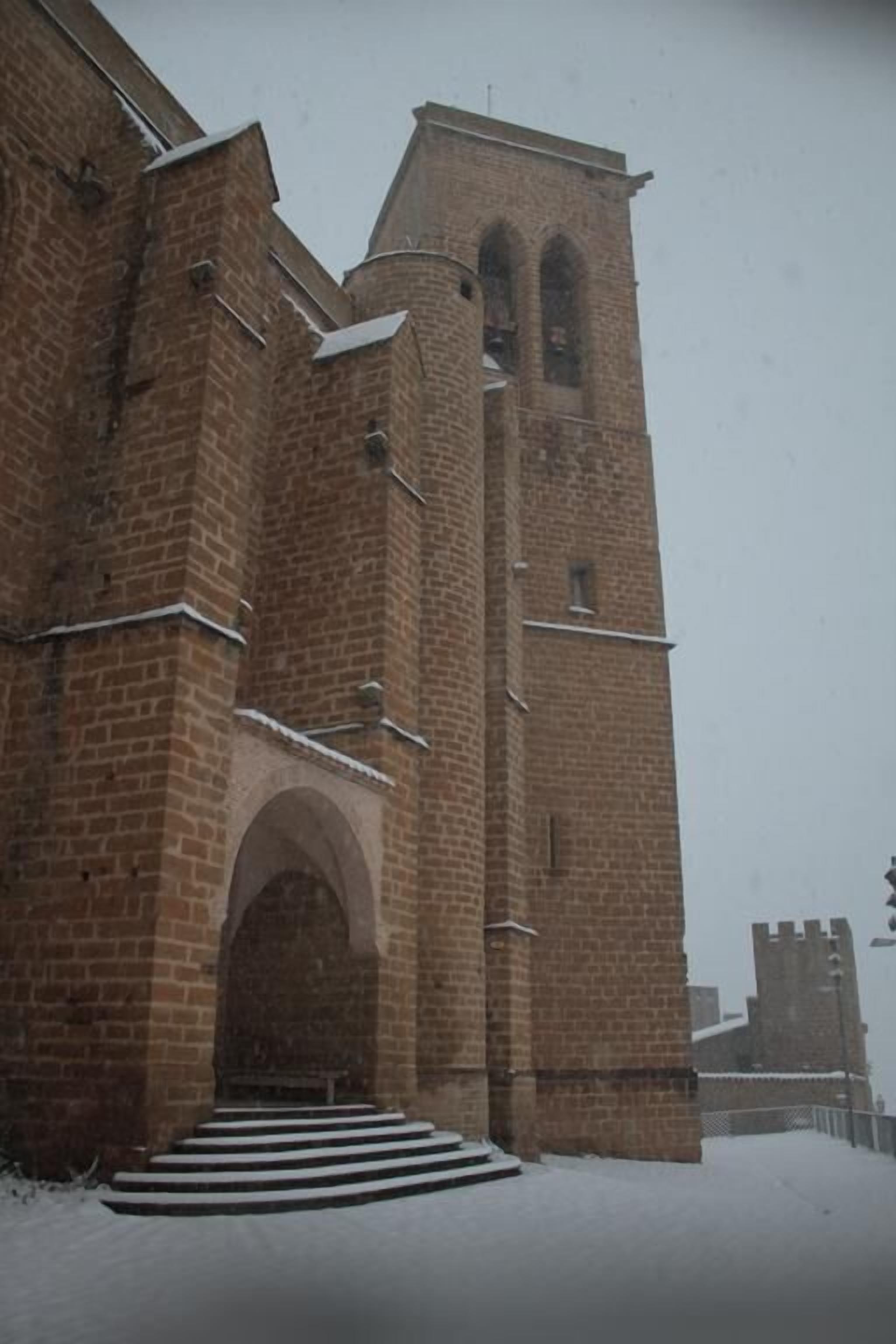 Un edificio de ladrillo con una amplia entrada en arco y una torre alta.