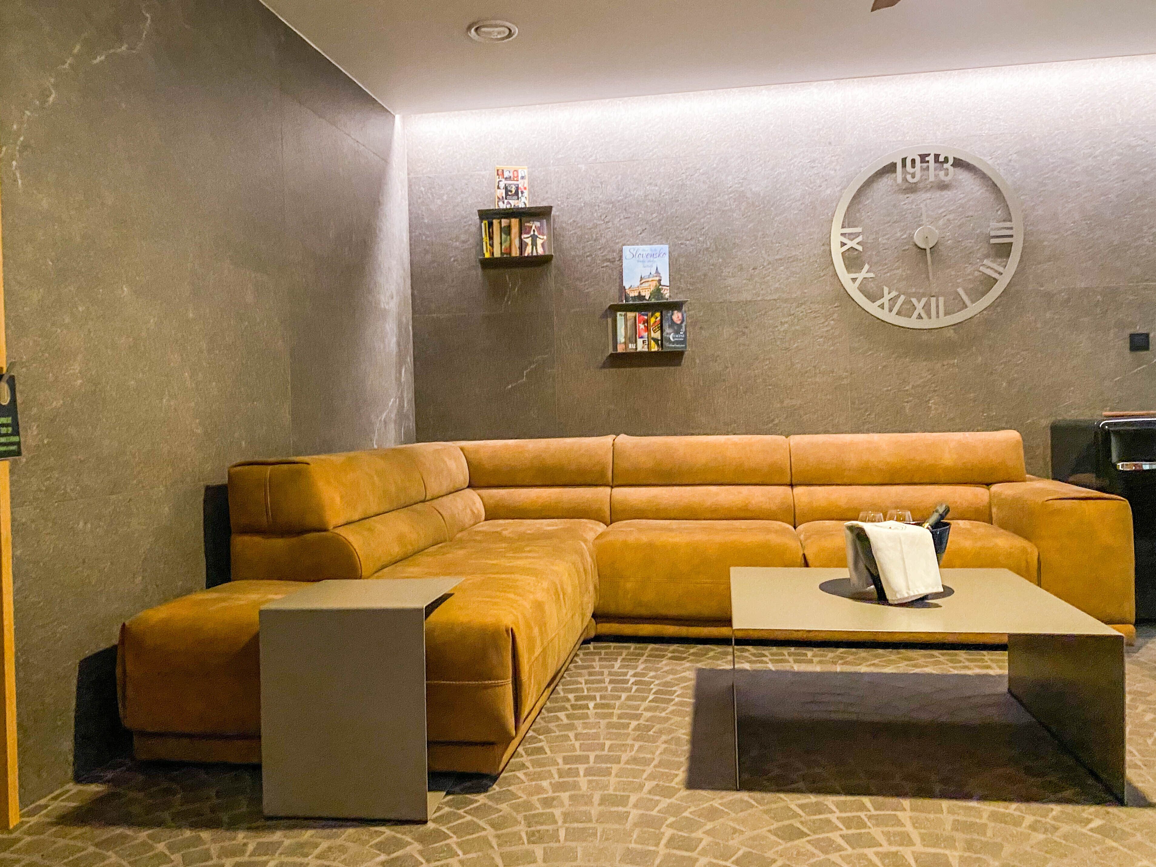 A modern living room with a sectional sofa, a coffee table, and a wall clock.