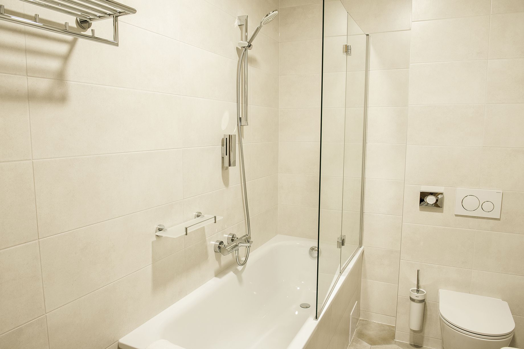 Een moderne badkamer met een douchecabine van glas, een wit bad en een toilet.