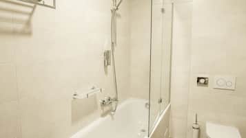 Een moderne badkamer met een douchecabine van glas, een wit bad en een toilet.