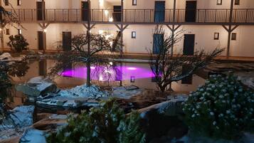 A hotel courtyard with a reflective pool, snow-covered ground, and a multi-story building with balconies.
