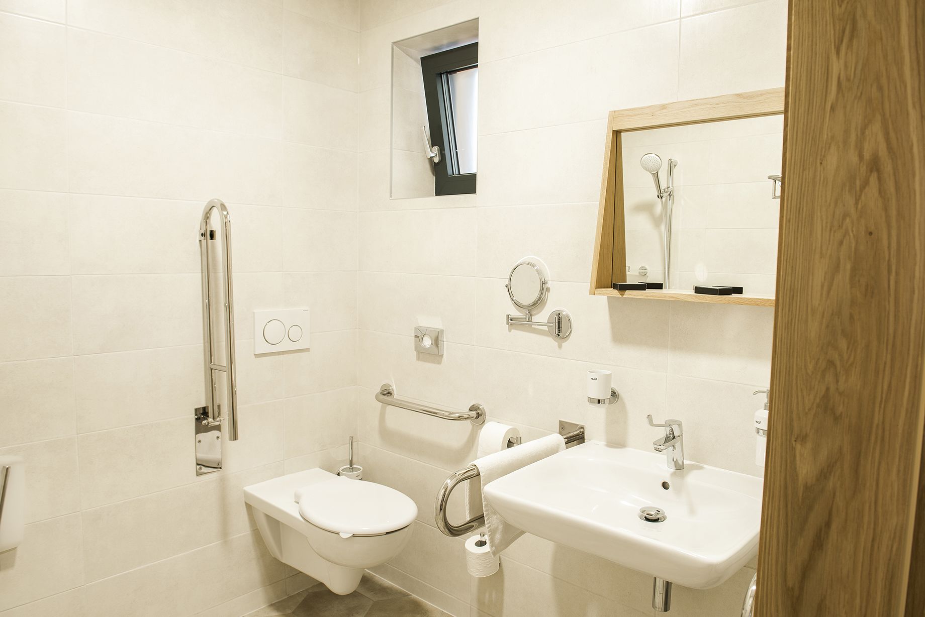 A modern bathroom with a toilet, bidet, and sink, equipped with a mirror and towel rack.