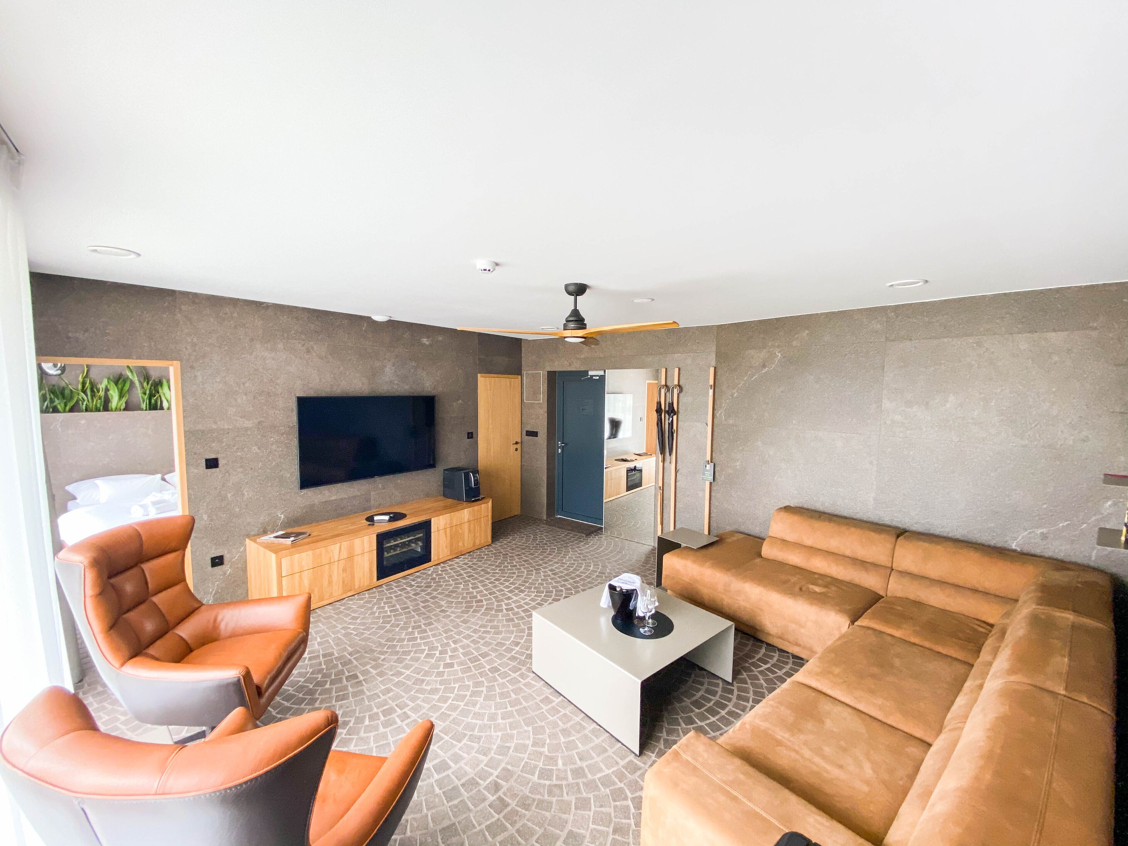 A modern living room with a large flat-screen TV, leather sofas, a coffee table, and a wooden entertainment unit.