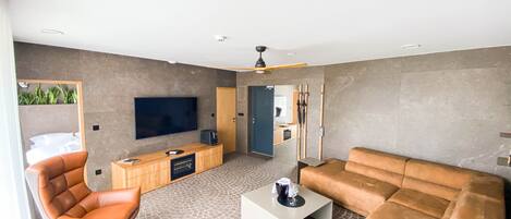 A modern living room with a large flat-screen TV, leather sofas, a coffee table, and a wooden entertainment unit.