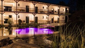 Un edificio de varios pisos con balcones y una piscina con iluminación morada.