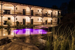 Un edificio de varios pisos con balcones y una piscina con iluminación morada.