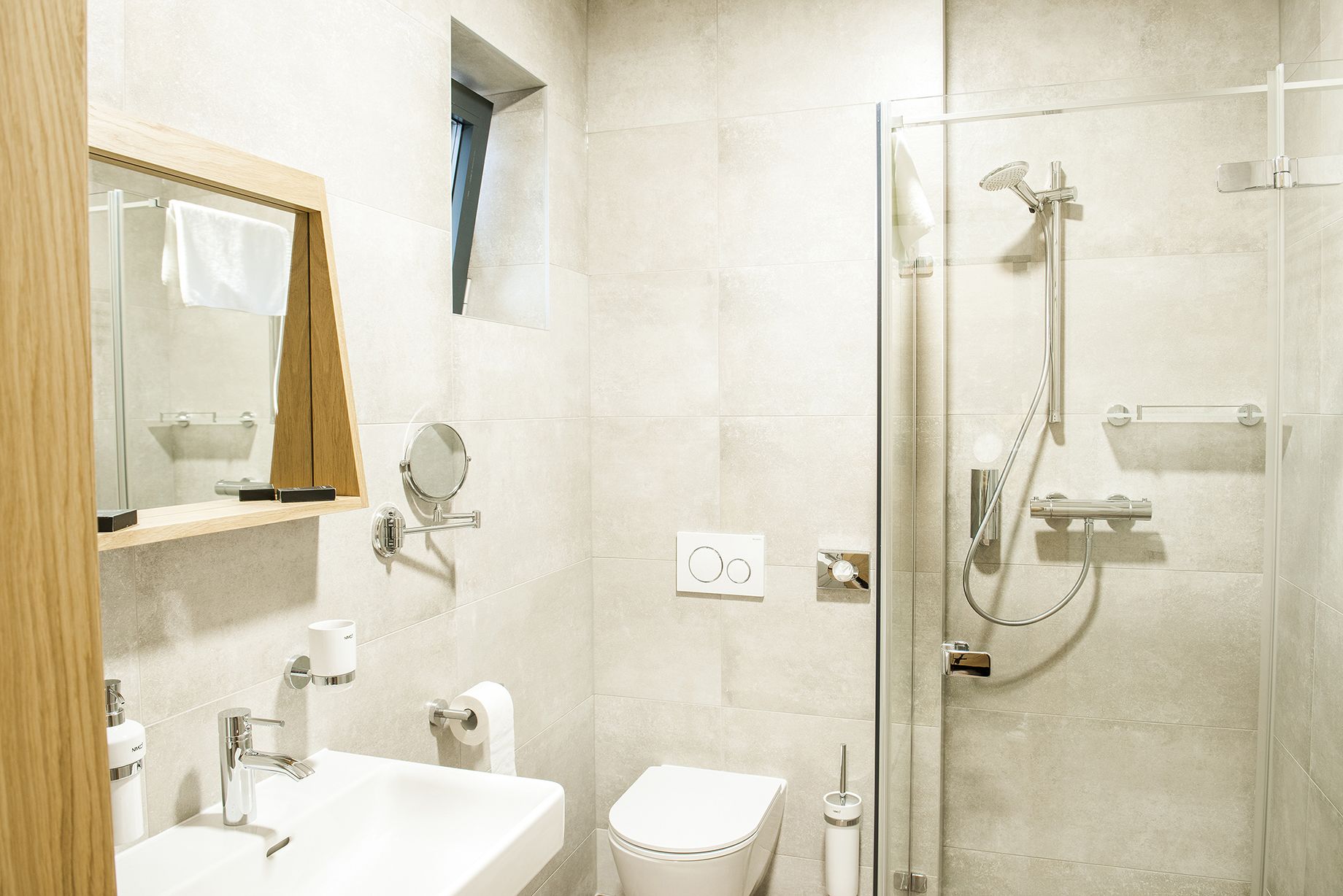 Une salle de bain moderne avec une douche à parois de verre, un meuble-lavabo en bois avec un miroir, des toilettes et un lavabo.