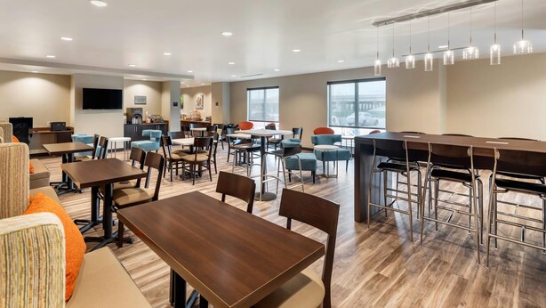 A modern dining area with multiple tables and chairs, a bar area, and large windows providing natural light. - Sleep Inn Lancaster Dallas South (Lancaster)
