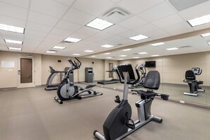 A fitness center with various exercise machines, a large mirror, and a sign indicating a safety zone. - Sleep Inn Lancaster Dallas South (Lancaster)