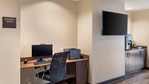 A business room with a desk, computer, chair, printer, and a mounted TV. - Sleep Inn Lancaster Dallas South (Lancaster)