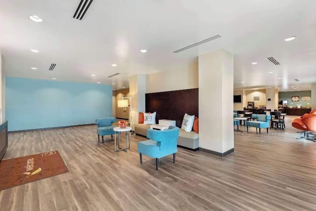 A modern hotel lobby with blue sofas, a reception desk, and a dining area.