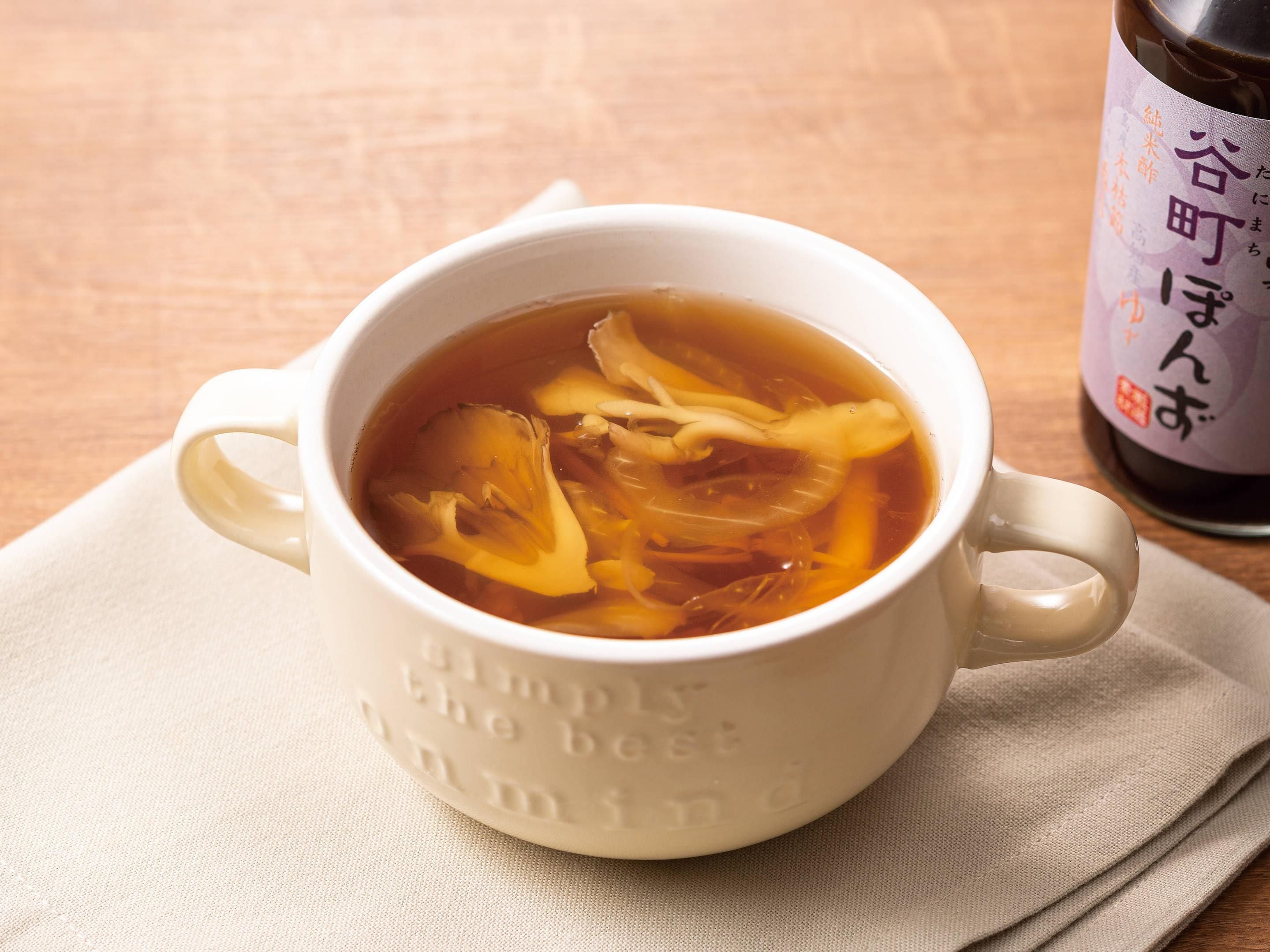 A white ceramic mug with embossed text, filled with a clear liquid and translucent items, placed on a beige cloth.