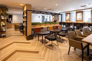 A modern cafe interior with wooden flooring, black mesh chairs, and a central wooden table. - Comfort Hotel Shin-Osaka (Osaka)