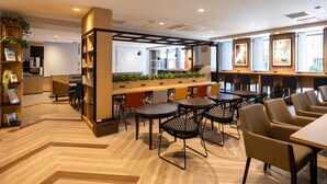 A modern indoor space with wooden flooring, seating areas, and a counter with plants. - Comfort Hotel Shin-Osaka (Osaka)