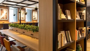 A modern library with a long wooden table, bookshelves, and framed pictures on the walls. - Comfort Hotel Shin-Osaka (Osaka)