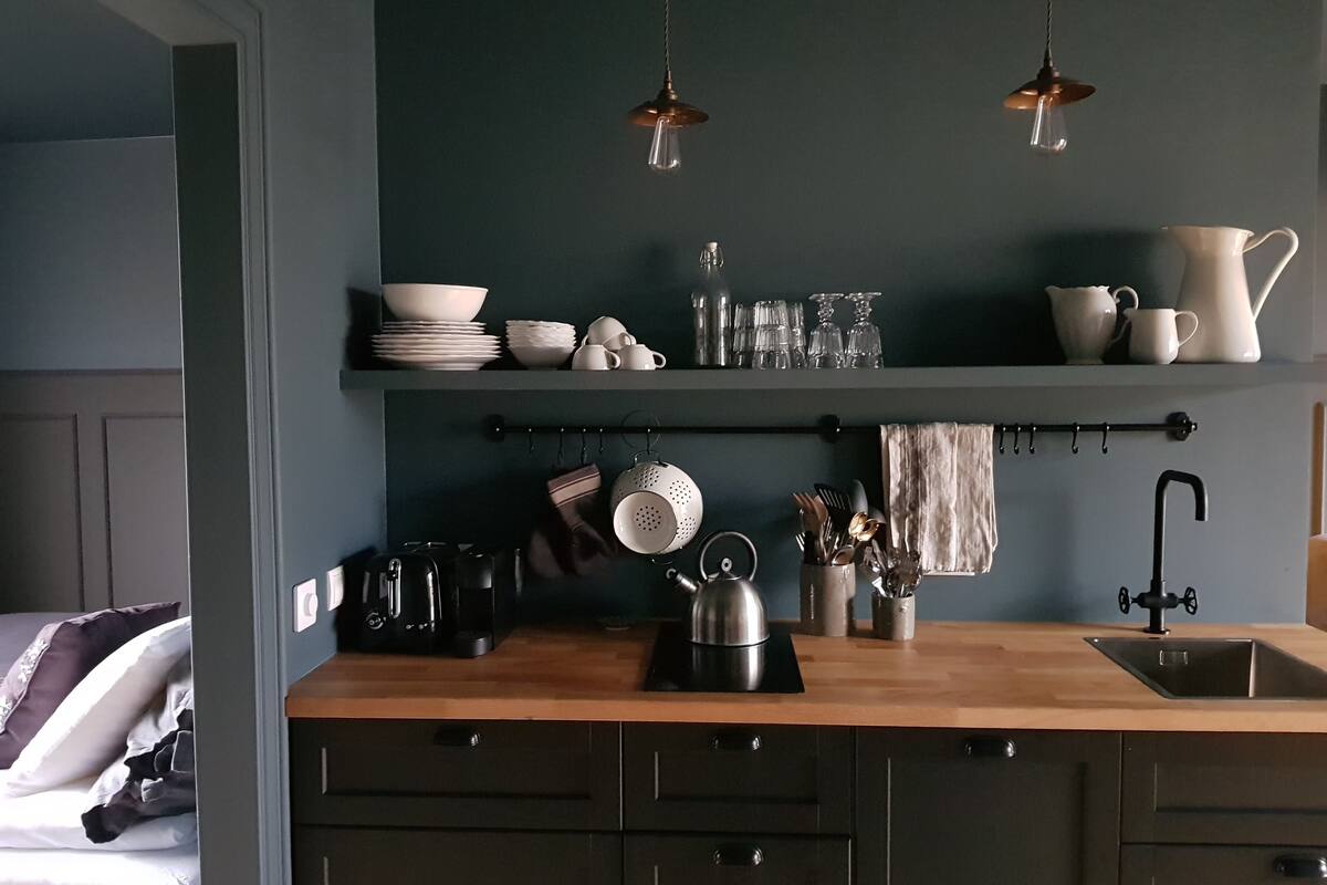 A kitchen with a wooden countertop, a kettle, a coffee maker, and various kitchen utensils.