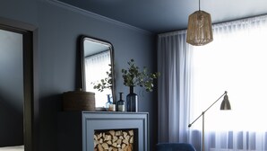 A modern living room with a fireplace, a green armchair, a blue armchair, and a floor lamp.