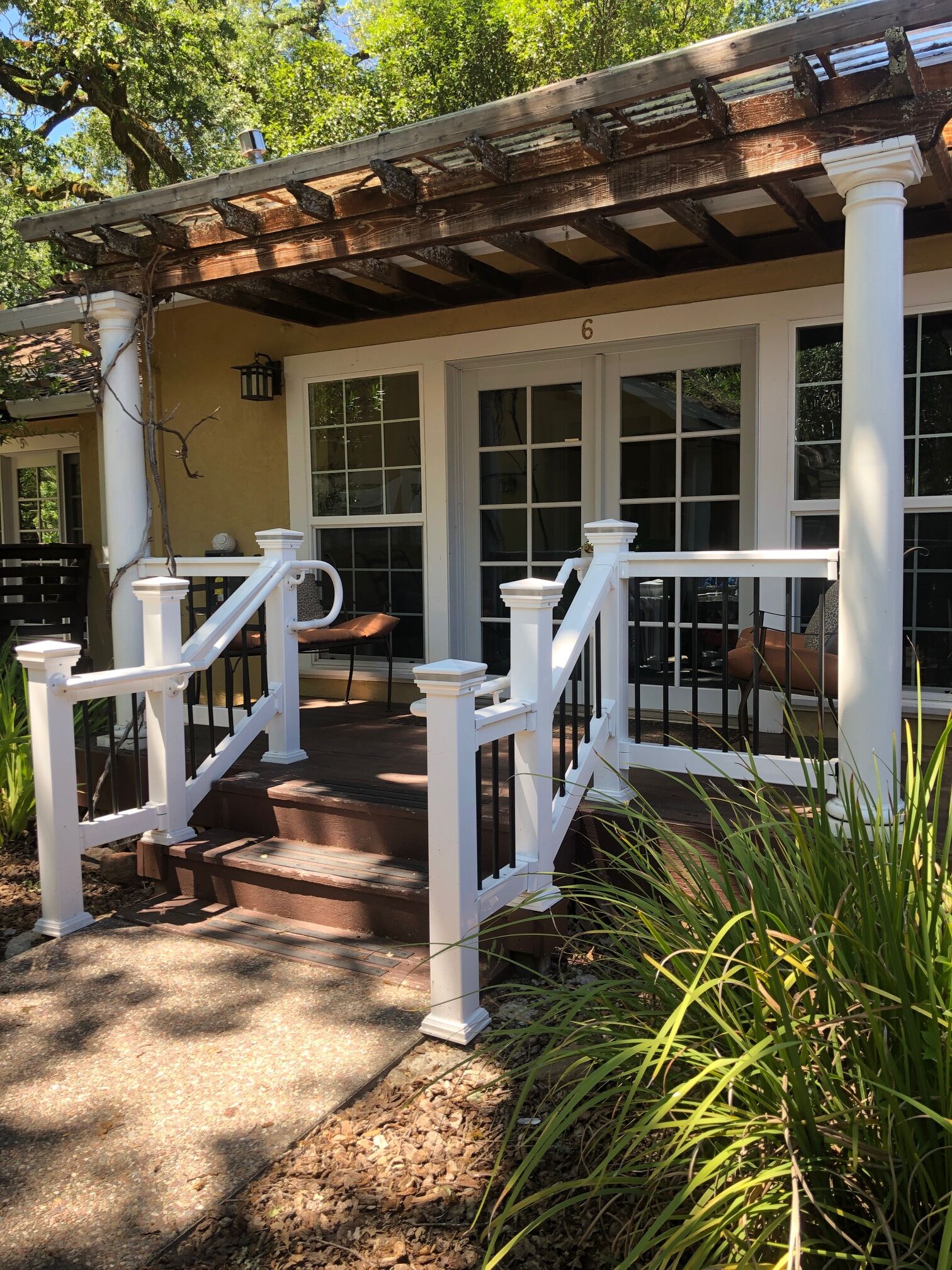 A covered porch with white railings and a wooden pergola.