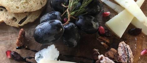 Una tabla de madera con una variedad de quesos, uvas, nueces y pan.