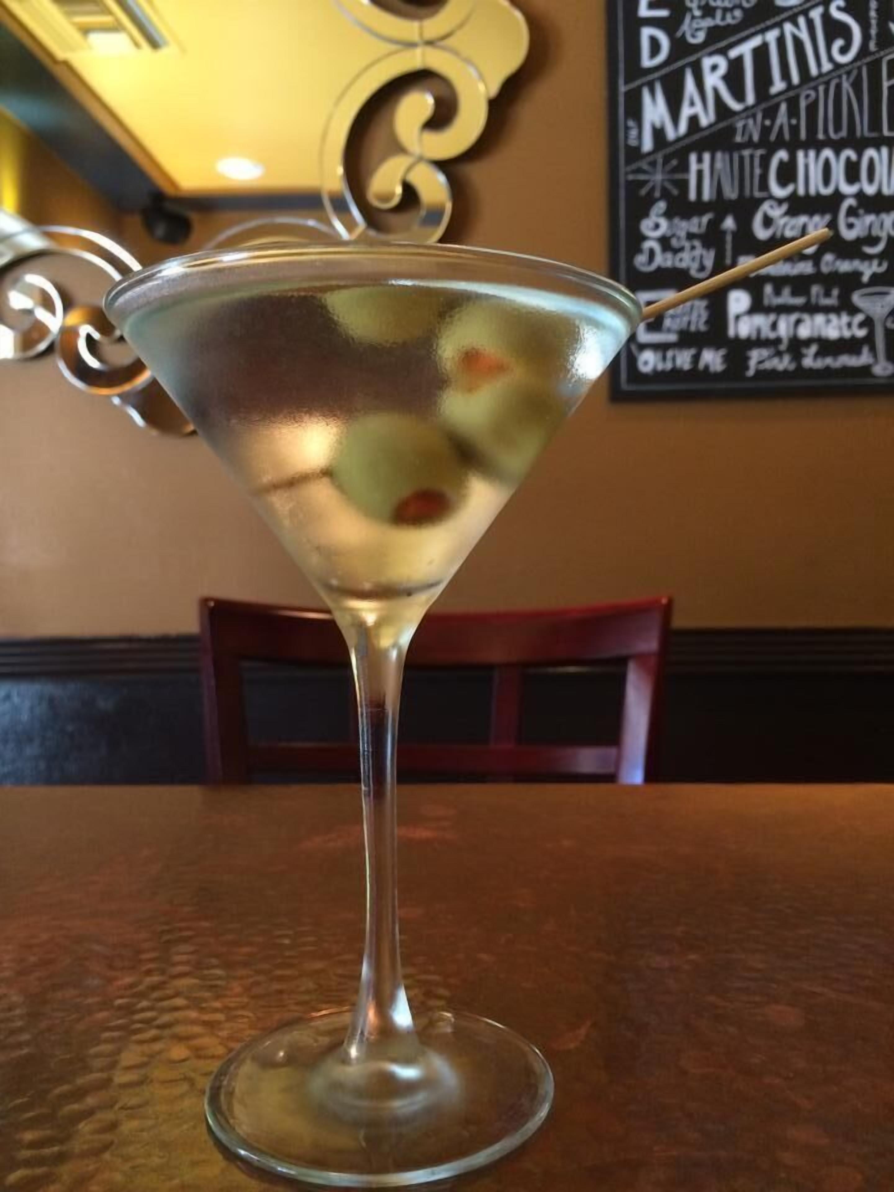 Ein Martini-Glas mit Oliven auf einem Tisch in einem Restaurant.