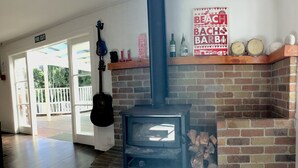 Una habitación con un estufa de leña, una guitarra y un cartel de 'Beach Boys' en la pared.