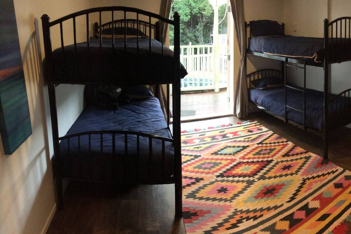 Un dormitorio con literas, una alfombra colorida y vistas al exterior.