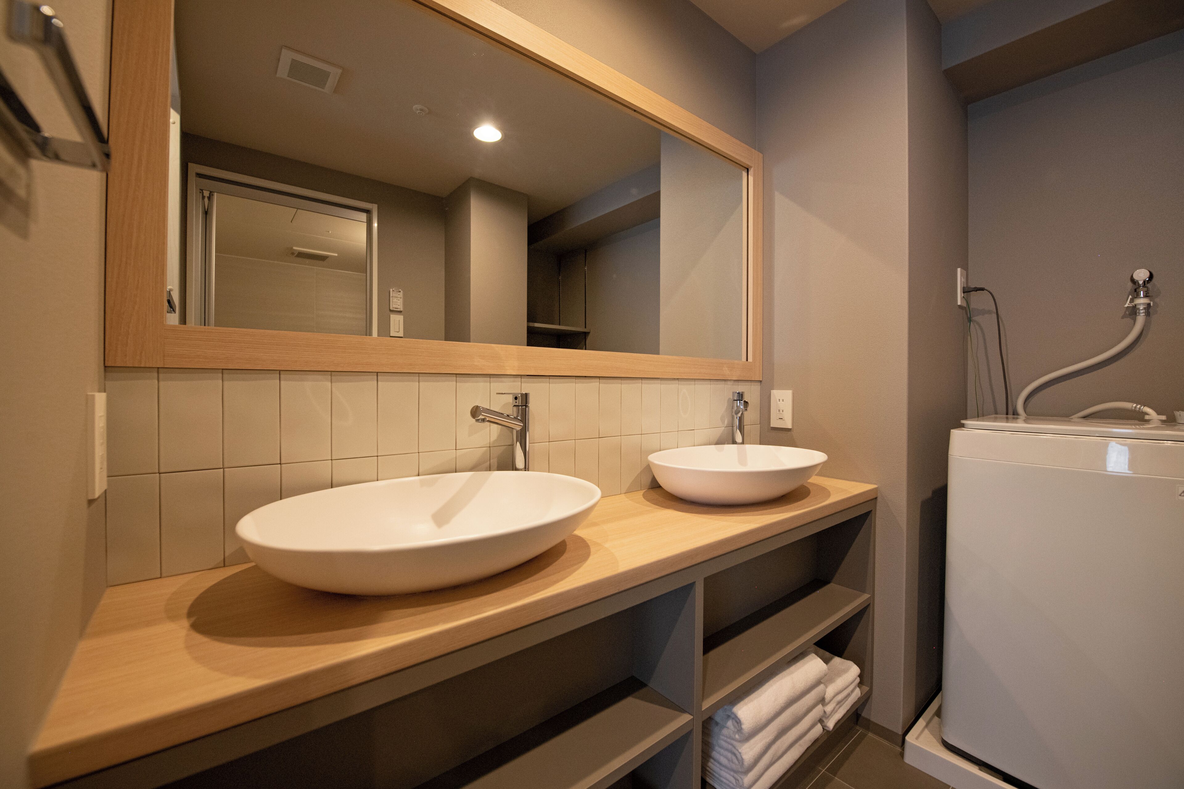 A bathroom with two sinks, a mirror, and a shower.