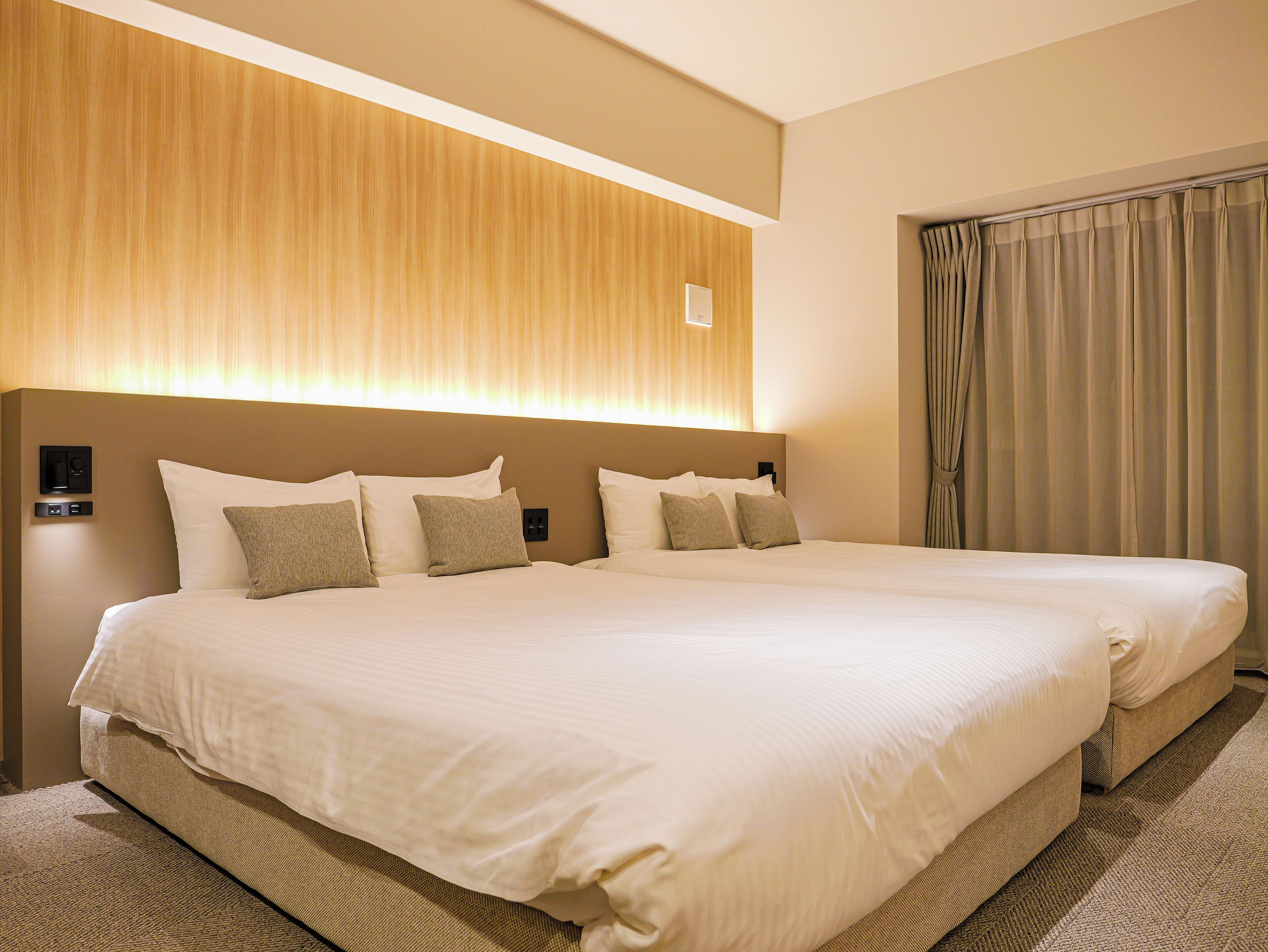A double bed with a headboard, a bedside table, and a wall-mounted control panel.
