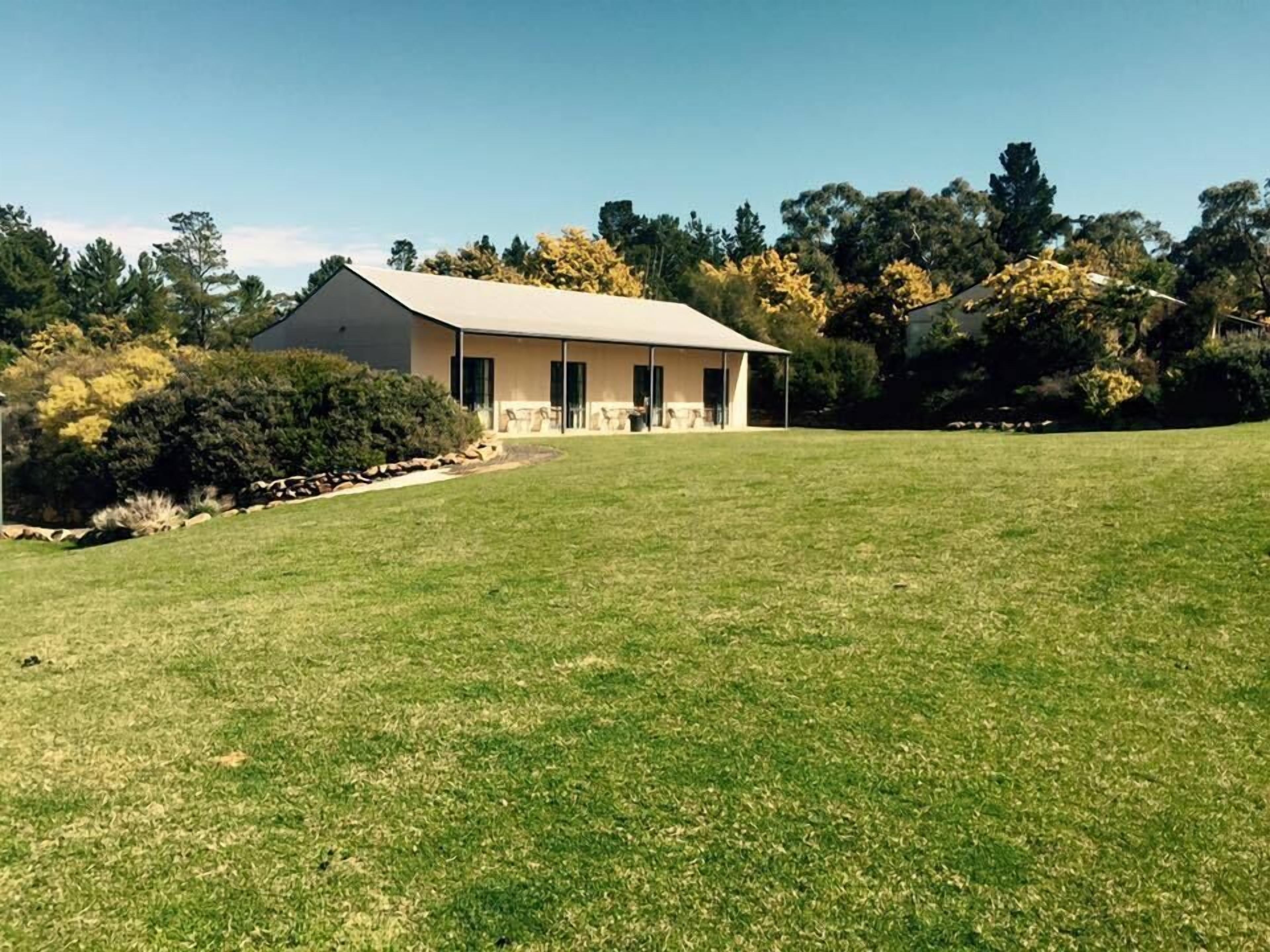 A house with a covered porch, surrounded by a well-maintained lawn and trees.