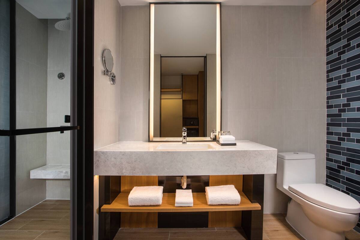 A modern bathroom with a large mirror, a sink, and a toilet.