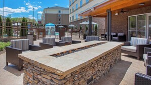 An outdoor patio area with stone seating, a fire feature, and a covered seating area with umbrellas. - Fairfield Inn & Suites by Marriott Pigeon Forge (Pigeon Forge)